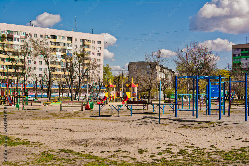 Public playground in the city without children. Colorful playground in the yard in the park surrounded by houses