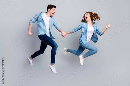 Full size photo of cheerful funky students spouses enjoy spring weekend rest jump hold hand run moving wear casual style outfit gumshoes isolated over gray color background