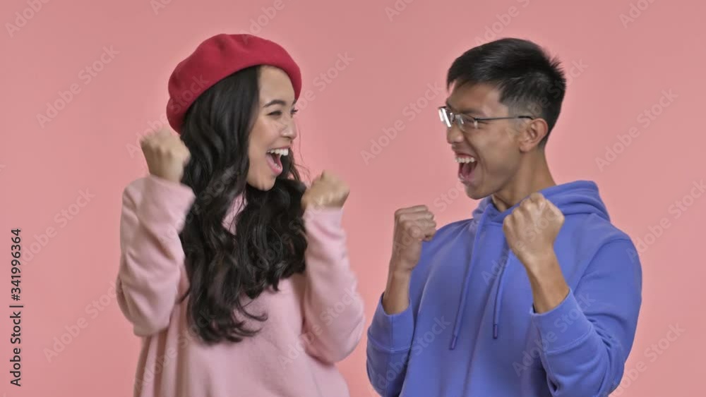 Young excited happy loving couple isolated over pink wall background showing winner gesture. Young excited happy loving couple isolated over pink wall background showing winner gesture.