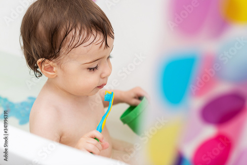 A one-year-old baby washes in the bathtub, plays with toys, learns to brush his teeth.