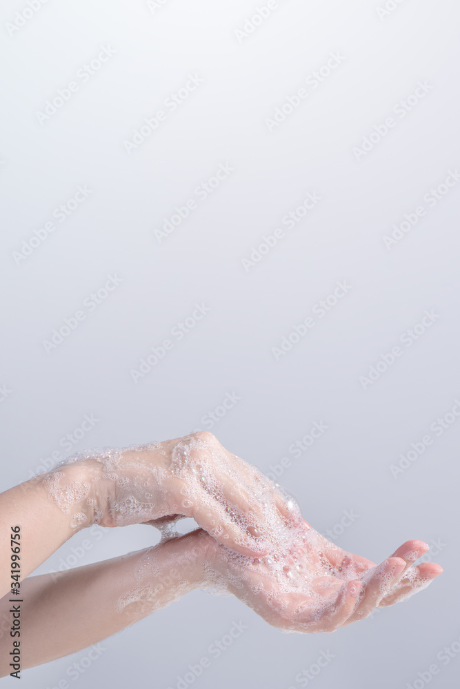 Washing hands. Asian young woman using liquid soap to wash hands, concept of hygiene to protective pandemic coronavirus isolated on gray white background, close up.