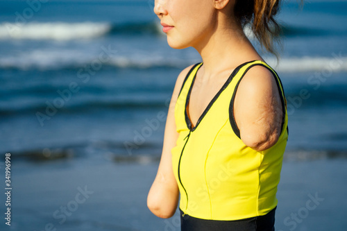 happy asian armless woman warming up before swimming at the tropical beach photo