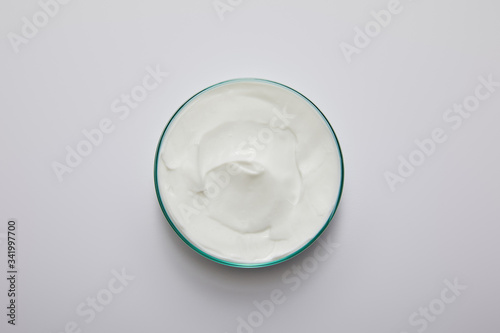 Top view of laboratory glassware with white cosmetic cream on grey background