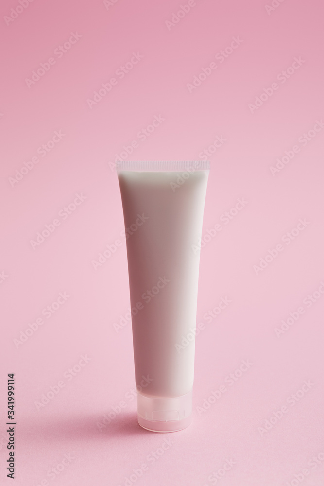 Plastic cosmetic cream tube on pink background Plastic cosmetic cream tube on pink background