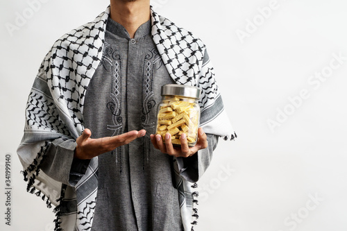 muslim hand gesture holding nastar snack over white photo