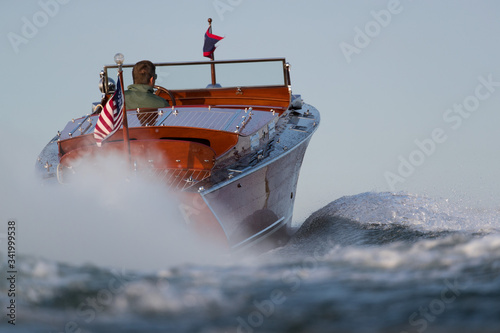 The rear of a speeding wood boat.