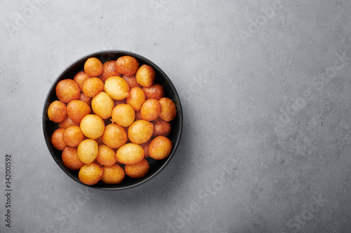 Loukoumades or luqaimat or lokma in black bowl on grey concrete background. Loukoumades is eastern cuisine donunts popular during Ramazan. Popular Ramadan Food. Iftar and Suhur sweets photo