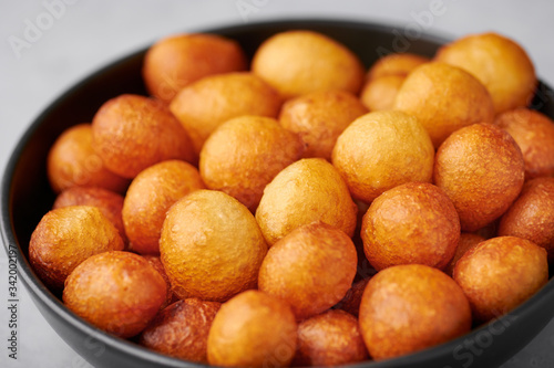 Loukoumades or luqaimat or lokma in black bowl. Loukoumades is an eastern cuisine donunts popular during Ramazan. Popular Ramadan Food. Iftar and Suhur sweets. Close up photo