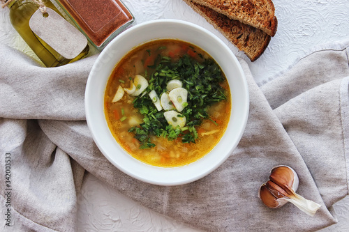 Lentil soup with garlic and herbs in a white bowl on the table. Diet, home-cooked food.