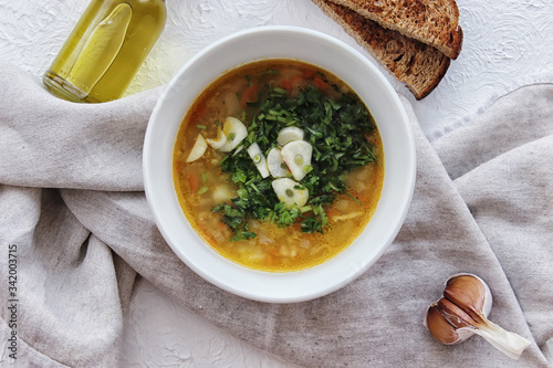 Lentil soup with garlic and herbs in a white bowl on the table. Diet, home-cooked food.