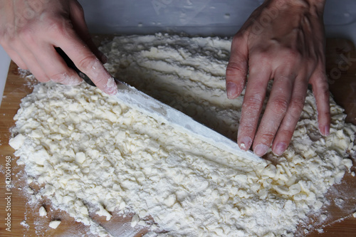The cook's hands chop butter and flour on a wooden Board with a knife. Homemade cake. Housework.