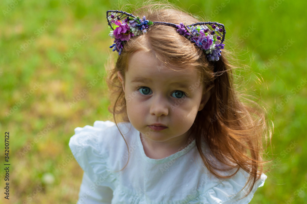 horizontal close-up portrait of a pretty two-year-old girl against the greenery of a summer park horizontal close-up portrait of a pretty two-year-old girl against the greenery of a summer park
