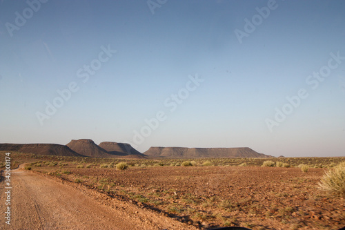 Dirt road in the desert with flat mountain on the horizon