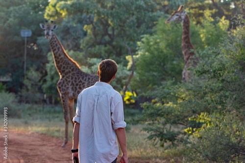 Tourist on the bush with giraffe on the background.