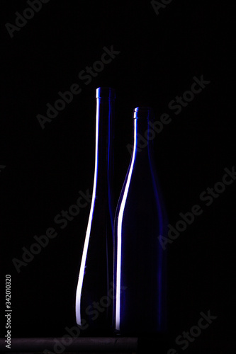two isolated empty glass bottles in a darkness