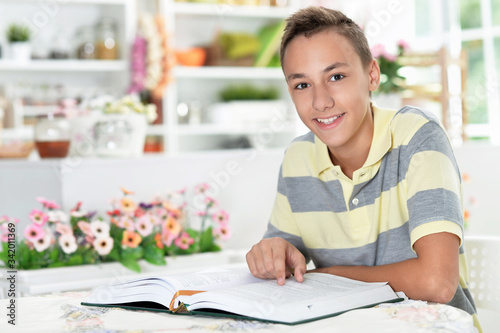 Smiling boy reading a book at the table