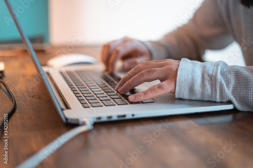 Hands pictured on the keyboard of a laptop typing something. 