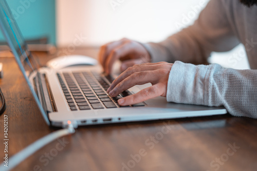 Hands pictured on the keyboard of a laptop typing something. 