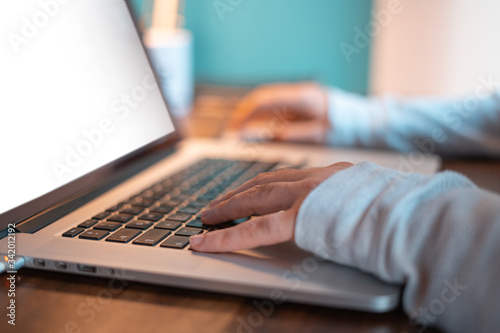 Hands pictured on the keyboard of a laptop typing something. 