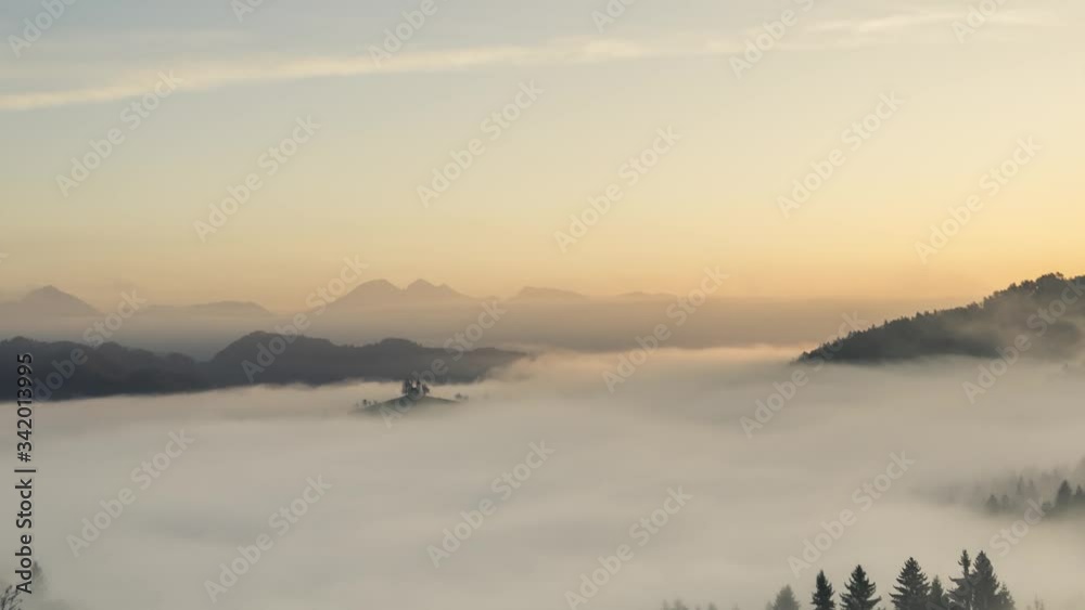 Zoom in time lapse of famous Saint Thomas church on hilltop with moving fog. In background Alps mountains. Amazing landscape nature in Slovenia. Well known spot photography spot. Golden hour sunrise Zoom in time lapse of famous Saint Thomas church on hilltop with moving fog. In background Alps mountains. Amazing landscape nature in Slovenia. Well known spot photography spot. Golden hour sunrise