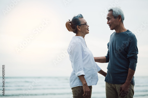 Romantic couple Enjoying senior walking travel on beach at sunset. Retirement age concept and love. © Pop Sujinun