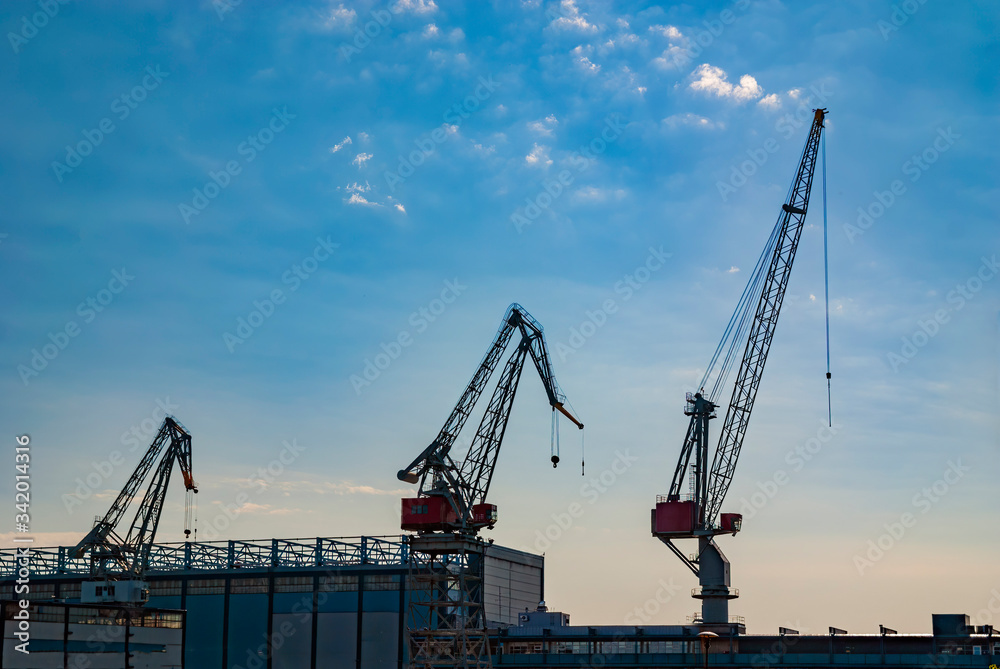 Cranes silhouettes in the harbor with blue sky background