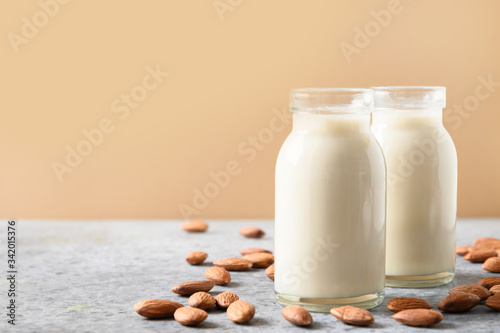 Fresh almond milk in glass bottle on beige. Close up.