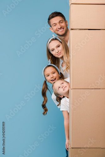happy parents and kids with cardboard boxes for relocation on blue