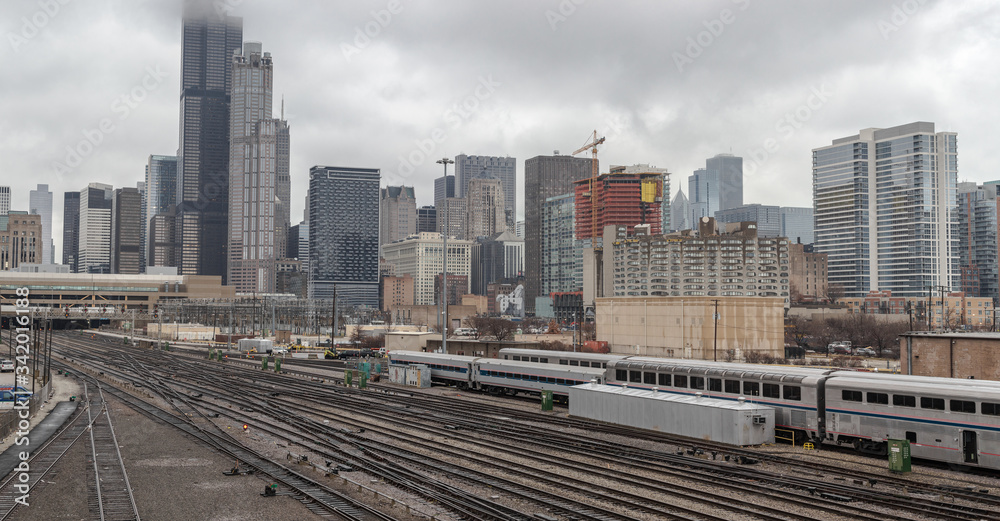 Wide angle view of partial Chicago skyline behind an active train yard on overcast day