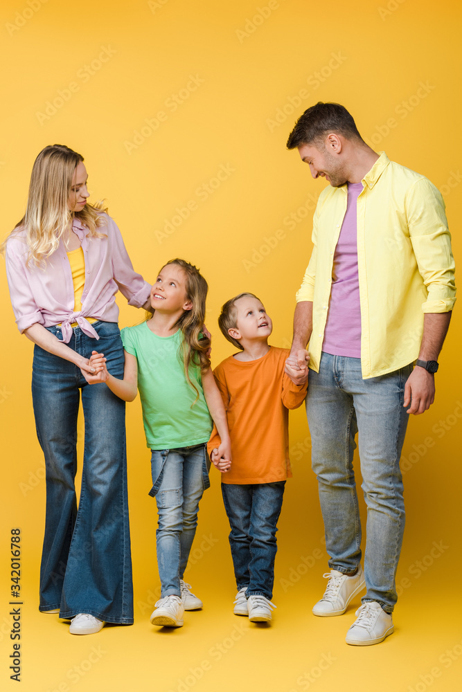 happy family holding hands with children on yellow happy family holding hands with children on yellow
