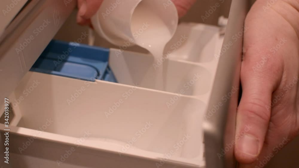 Housewife adding liquid detergent to compartment in washing machine and