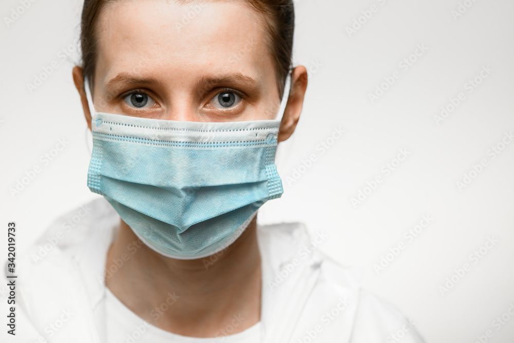 Close-up face of woman in medical mask and white protective suit on white backgroung. Close-up face of woman in medical mask and white protective suit on white backgroung.