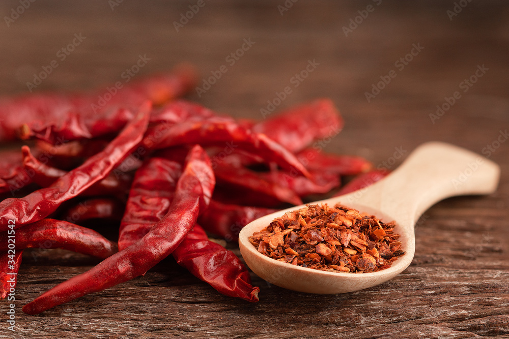 Dried red chili on wooden table.Chili powder on a wooden spoon Dried red chili on wooden table.Chili powder on a wooden spoon