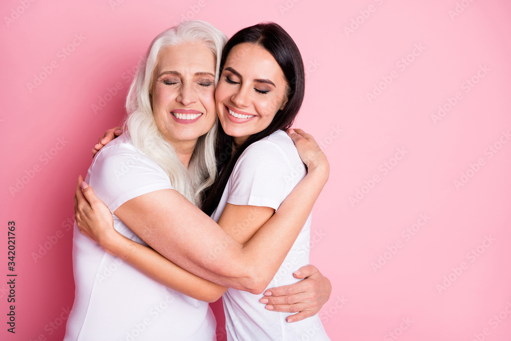 Photo of charming aged mother young daughter two ladies generation hug cozy best friends finally together wear casual white t-shirts isolated pastel pink color background Photo of charming aged mother young daughter two ladies generation hug cozy best friends finally together wear casual white t-shirts isolated pastel pink color background