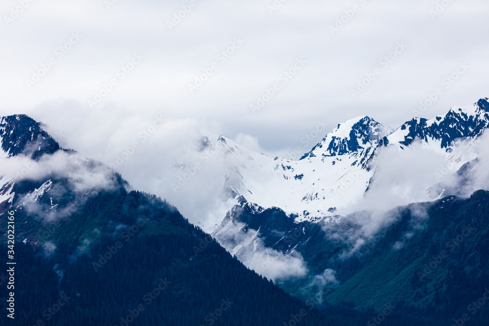 Snow capped rugged rocky mountains in clouds on the Kenai Peninsula of Alaska Snow capped rugged rocky mountains in clouds on the Kenai Peninsula of Alaska