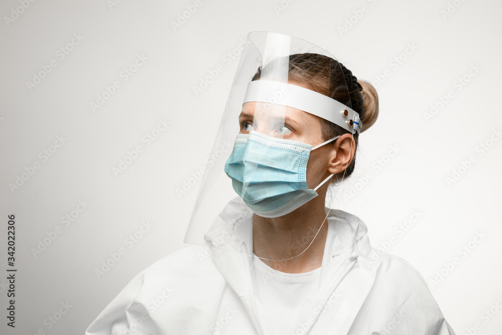young woman in medical mask and protective shield on her head looking away. young woman in medical mask and protective shield on her head looking away.