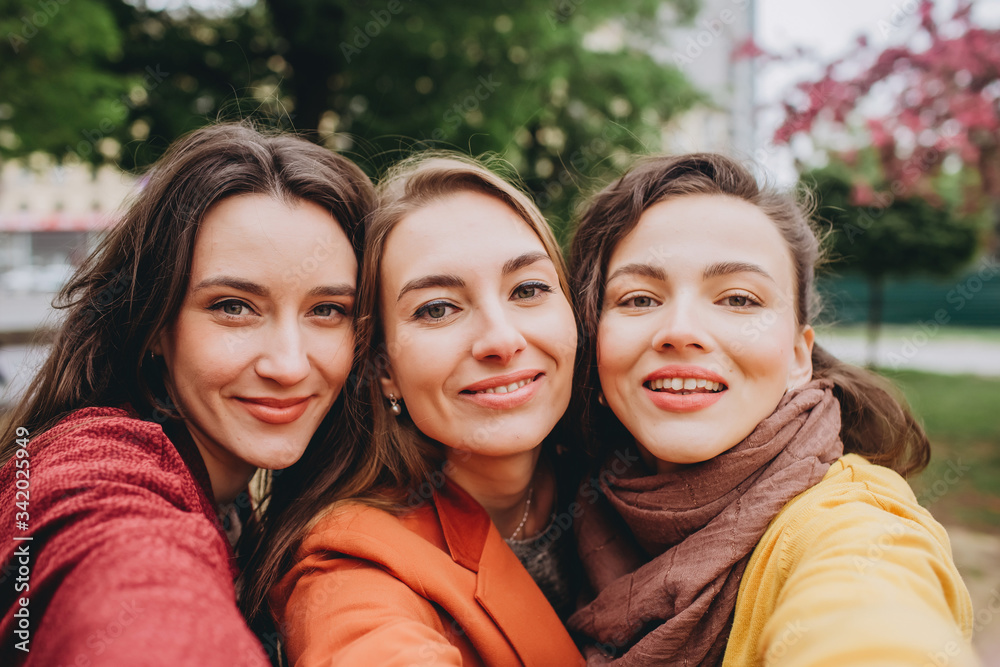 Obraz premium Best friends girls having fun, joy. Lifestyle. Beautiful young women in sunglasses dressed in the nice clothes smiling on a sunny day. photos of girls against the background of flowering trees