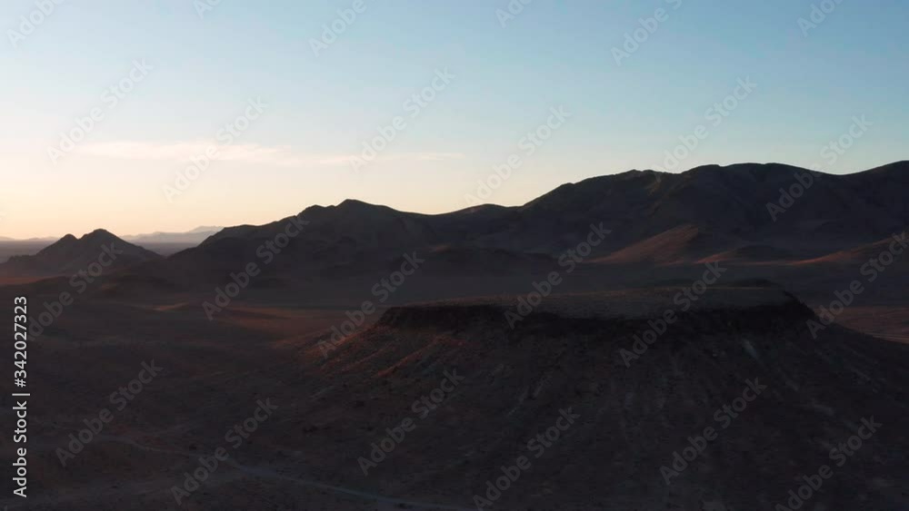 An aerial shot of morning sunshine illuminating a mesa and surrounding BLM land to the west of Pahrump, NV. In the background, a lone car travels on the Bob Rudd Highway/Bell Vista Road. An aerial shot of morning sunshine illuminating a mesa and surrounding BLM land to the west of Pahrump, NV. In the background, a lone car travels on the Bob Rudd Highway/Bell Vista Road.