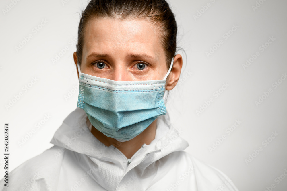 Portrait of woman with blue eyes and sad expression in medical mask for protection against influenza. Portrait of woman with blue eyes and sad expression in medical mask for protection against influenza.