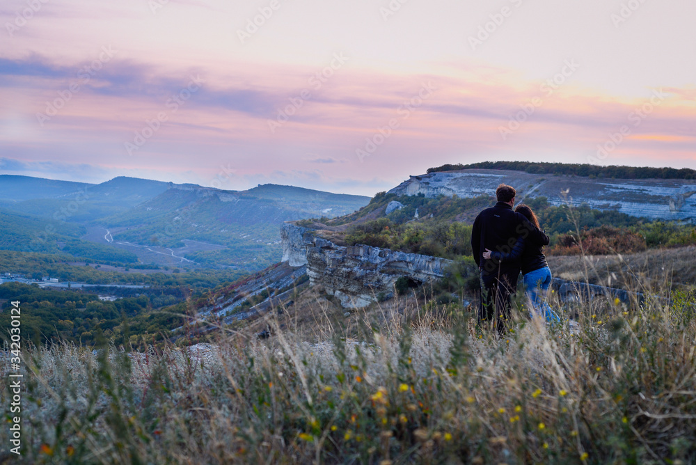 Couple in love. Two people watch sunset inthe mountains. Landscape background.