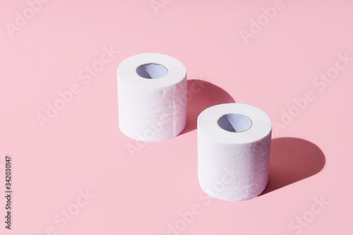 Creative top view image with rolls of toilet paper, hot commodity during covid-19 and period of self isolation. Pink background, copy space