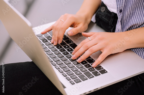 young woman hands texting on grey laptop with black keyboard