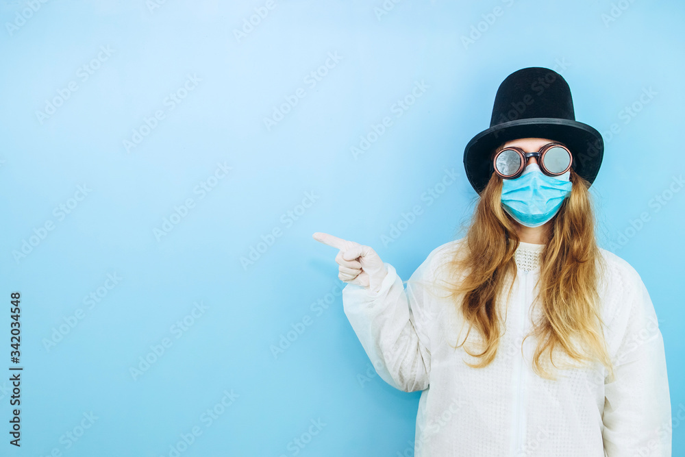 Creative girl in a white robe, medical mask, glasses and a hat on a blue background. Self-isolation during coronavirus quarantine. Epidemic covid-2019. Creative girl in a white robe, medical mask, glasses and a hat on a blue background. Self-isolation during coronavirus quarantine. Epidemic covid-2019.