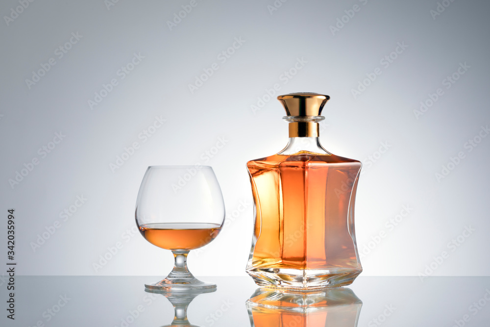 close up view of bottle of whiskey and a glass aside on grey back. close up view of bottle of whiskey and a glass aside on grey back.