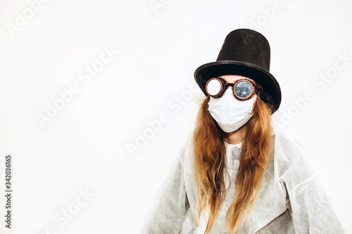 Creative girl in a white robe, medical mask, glasses and a hat on a white background. Self-isolation during coronavirus quarantine. Epidemic covid-2019. © Stanislav