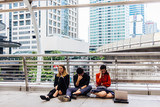 Young multi-ethnic employees are sitting sad, anxious and stressed along the sidewalk on the Sky walk. The concept of being dismissed and fired