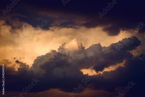 Dark, dramatic nimbus clouds at sunset, lit by the last rays of sunlight before a storm. © Hernan Schmidt