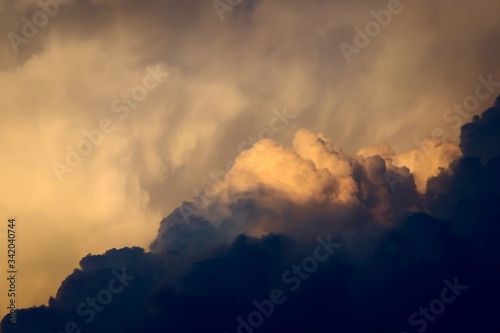 Dark, dramatic nimbus clouds at sunset, lit by the last rays of sunlight before a storm.