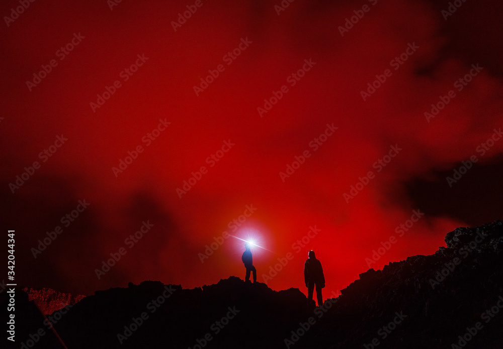 Fototapeta premium Two tourists with the headlights at the edge of Nyiragongo volcano