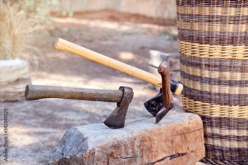 old rusty axes nailed to a piece of tree trunk.